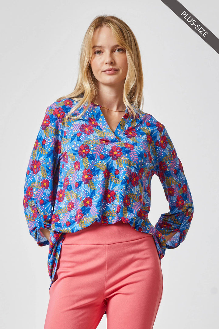Model wearing the Lizzy medallion blouse tucked into coral pants, highlighting the flowy fit and vibrant summer colors.