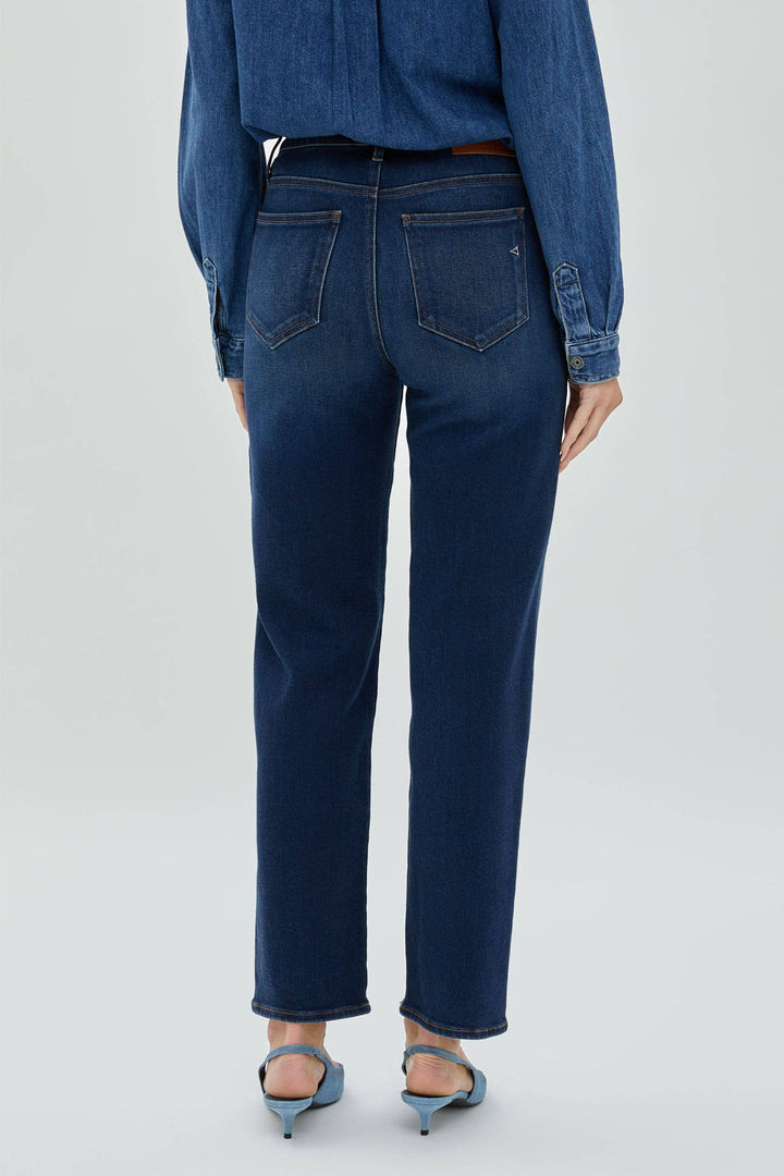Woman wearing a dark denim standing with her back to the camera.