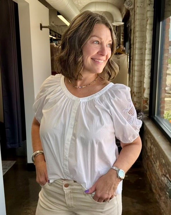 Dear John Denim Emiline Puff Sleeve Embroidered Top in White, gathered scoop neck and button placket styled with tan corduroy, front view on model