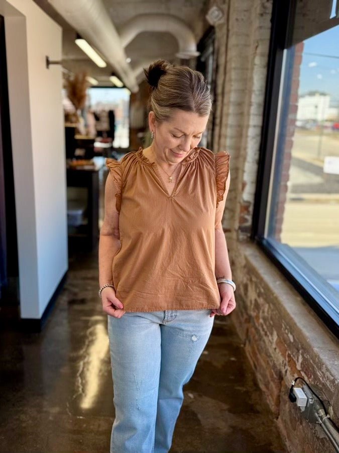 Our model is wearing a size Small in the biscuit Puja Top by Dear John Denim, shown full-length paired with light wash distressed straight-leg denim, styled with gold jewelry and a beaded bracelet.