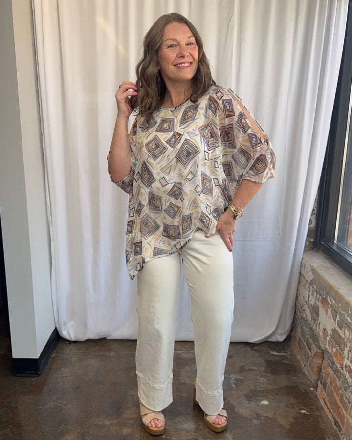 Lior Geometric Diamond Print Asymmetrical Blouse in cream with multicolor diamond print, asymmetrical drape and 3/4 sleeve detail, side view on model
