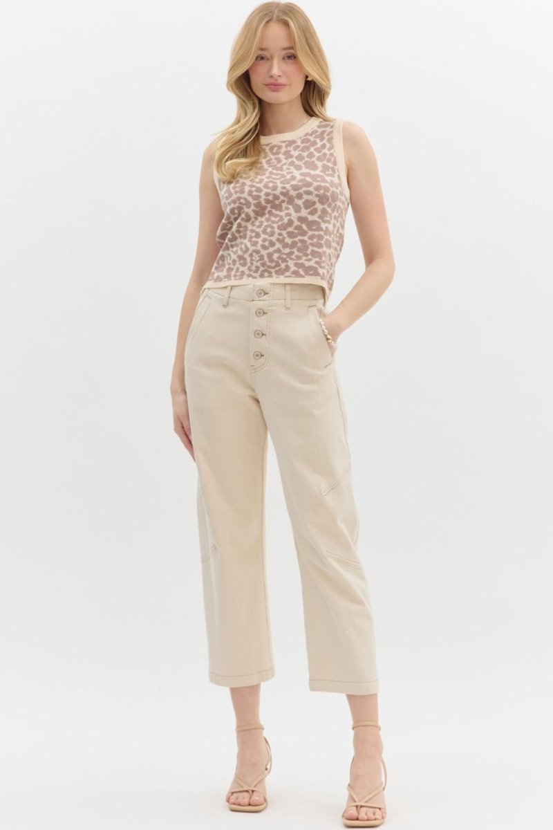 Woman wearing a leopard print top and beige pants on a white background