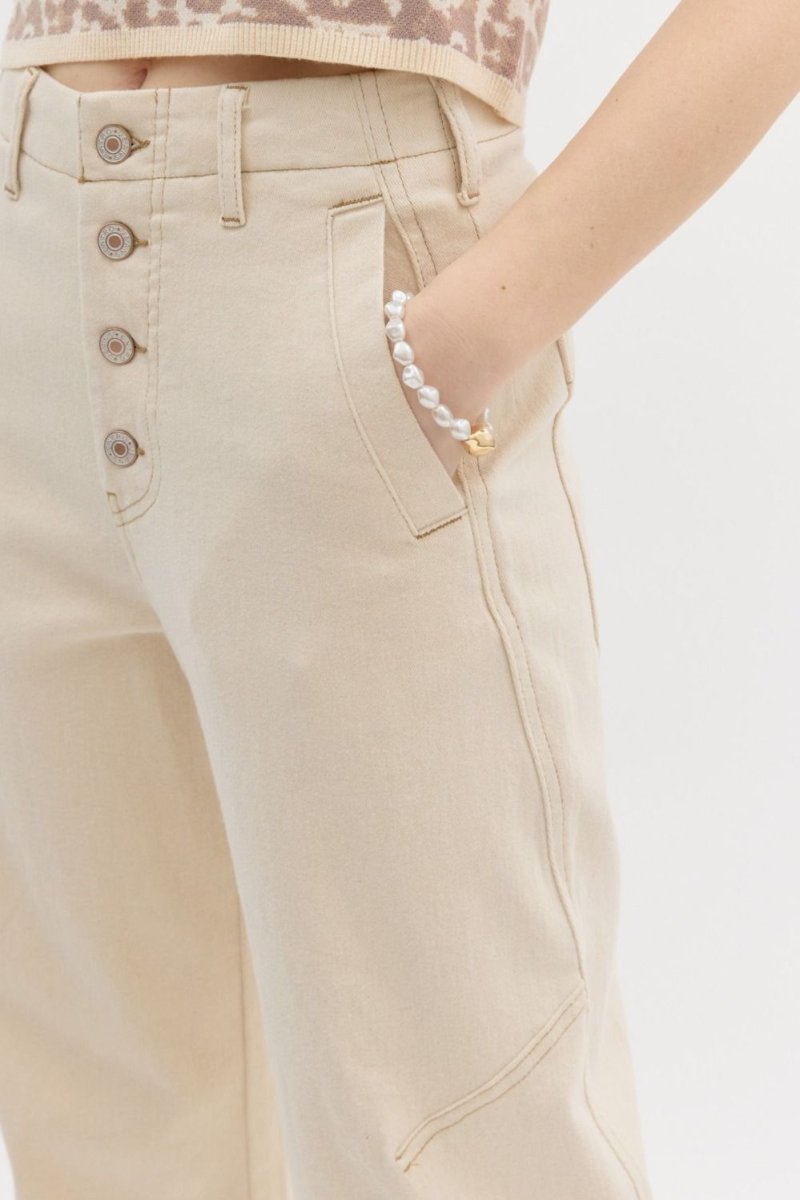 Beige pants with button details on a plain background
