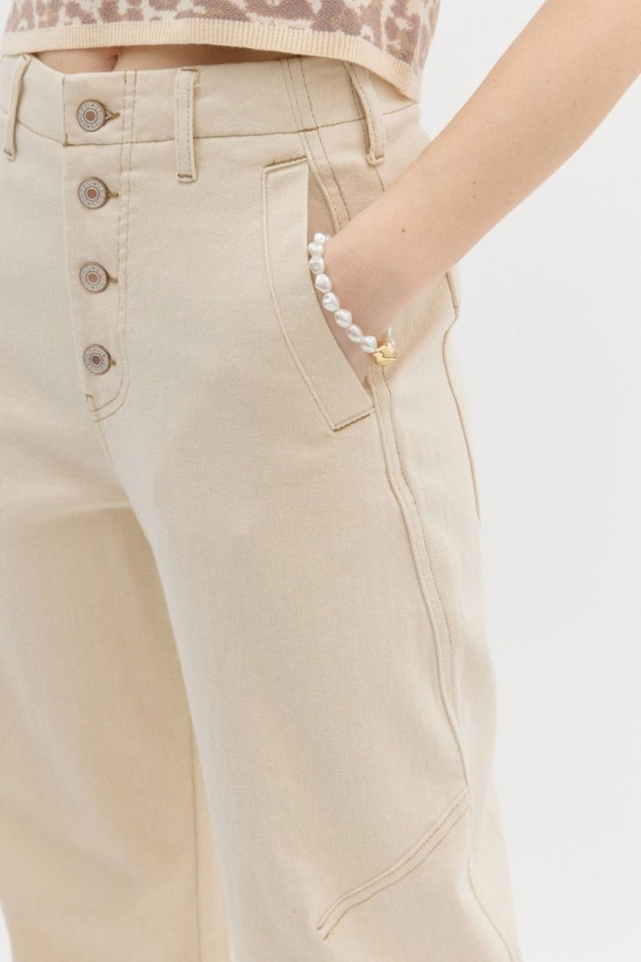 Beige pants with button details on a plain background