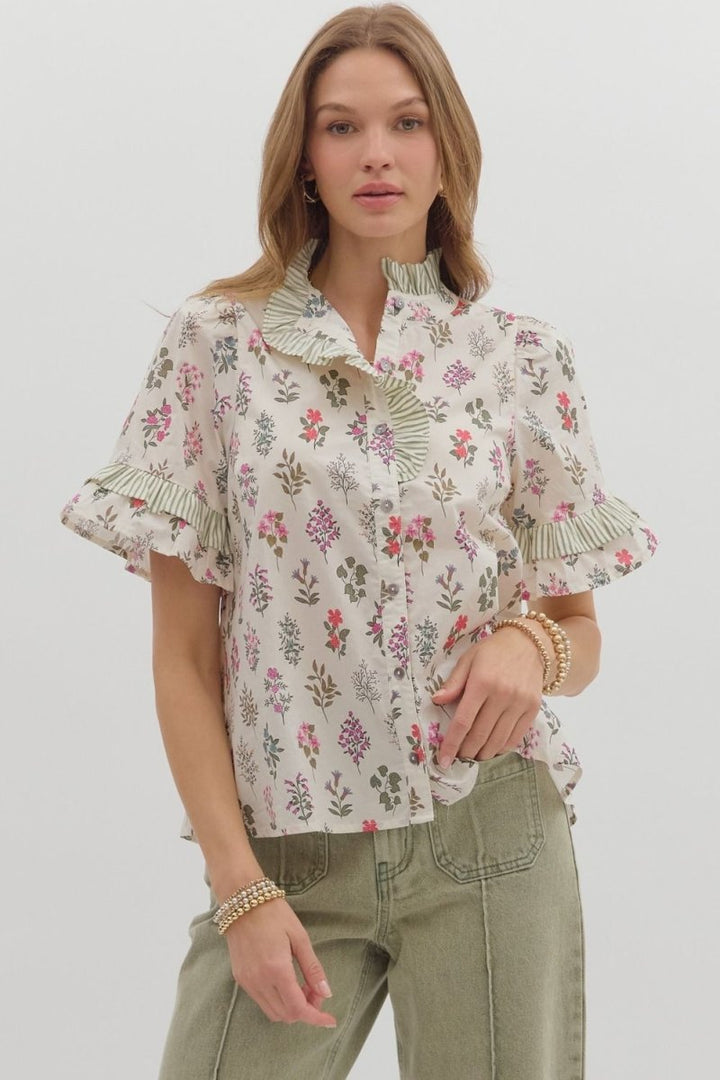 Woman wearing Entro floral button-front top with striped ruffle neckline and puff sleeves with olive pants.