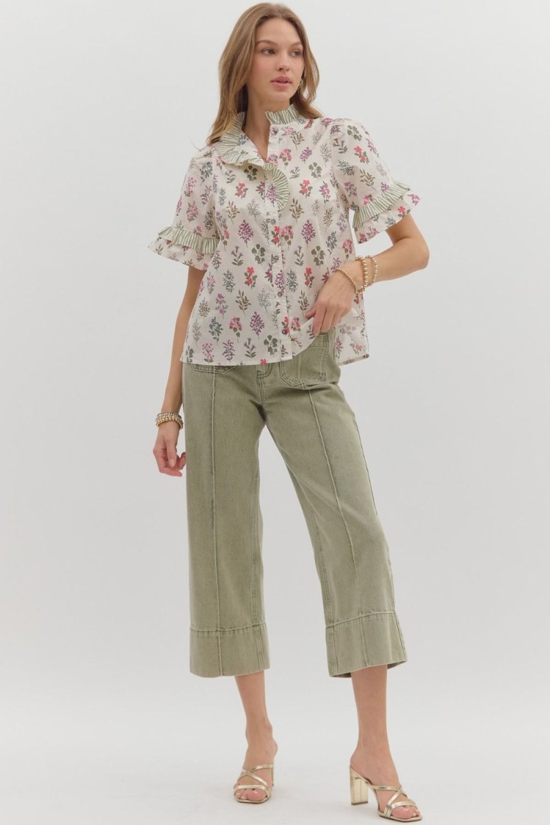 Woman wearing a floral blouse and green pants on a white background