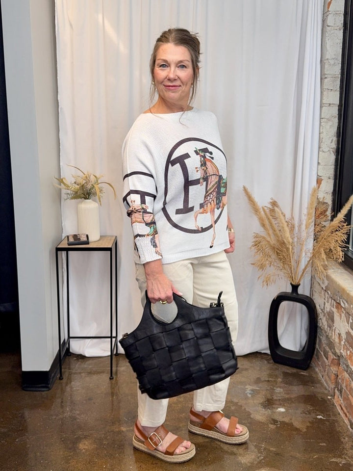 Side view showing the draped batwing sleeves and comfortable fit of the equestrian print knit.
