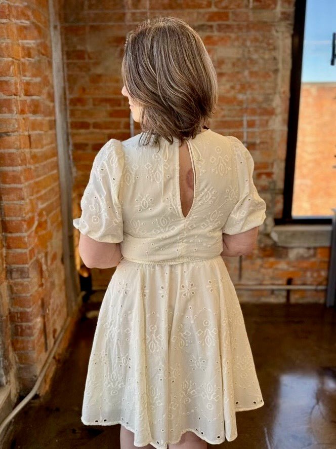 Black Tape Eyelet Belted Mini Dress in Ecru, keyhole back cutout with puff sleeves and eyelet floral skirt, back view on model
