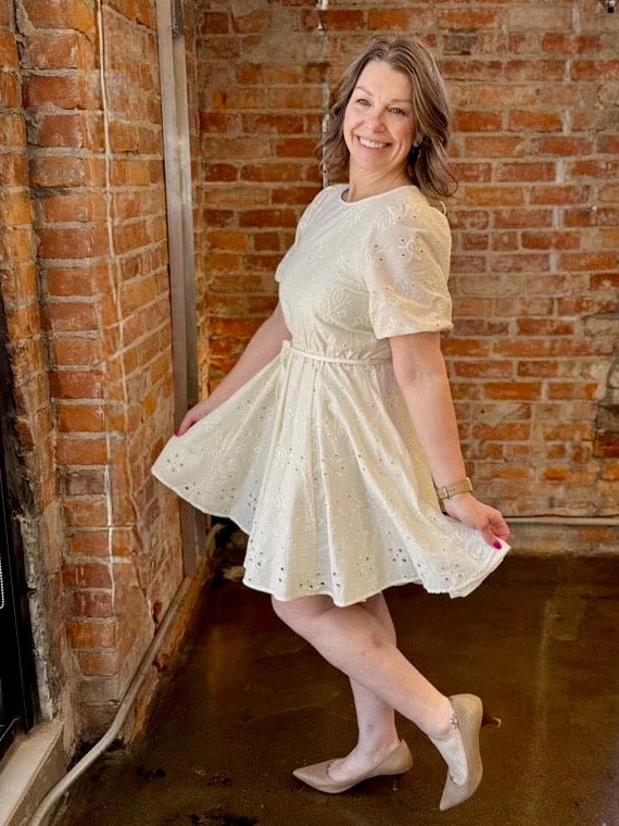 Black Tape Eyelet Belted Mini Dress in Ecru, full flared eyelet skirt with rope belt styled with nude pumps, lifestyle view on model
