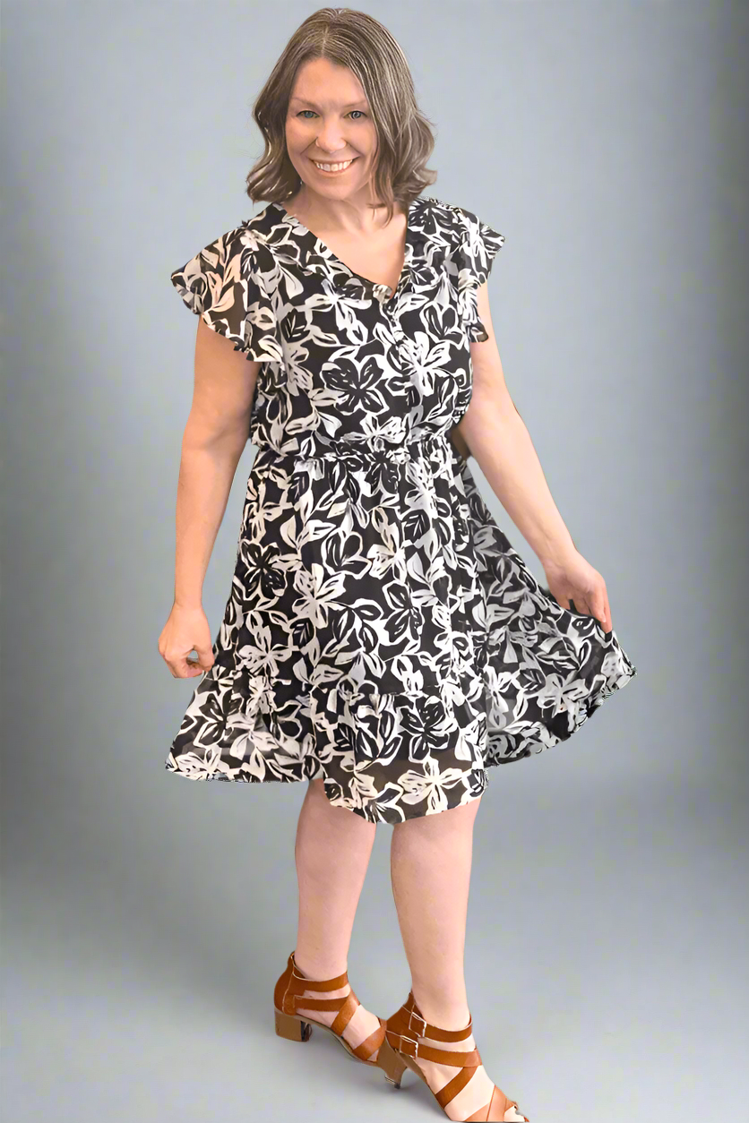 Front view of the Floral Chiffon Ruffle Dress in a black and white floral print featuring flutter sleeves and a flounce hem.