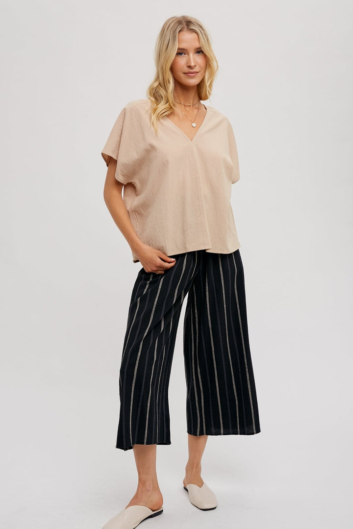 woman wearing a beige FUN2FUN V-neck top with dolman sleeves, showcasing and black stripe bottom.