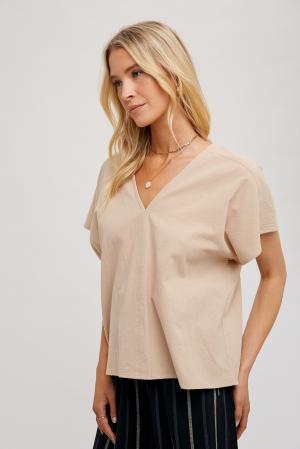 woman wearing a beige FUN2FUN V-neck top with dolman sleeves, showcasing the side view.