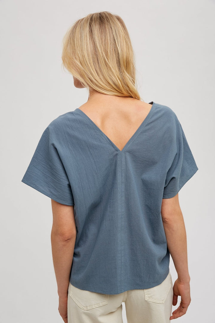 woman wearing a beige FUN2FUN V-neck top with dolman sleeves, showcasing the v-neck in the back.