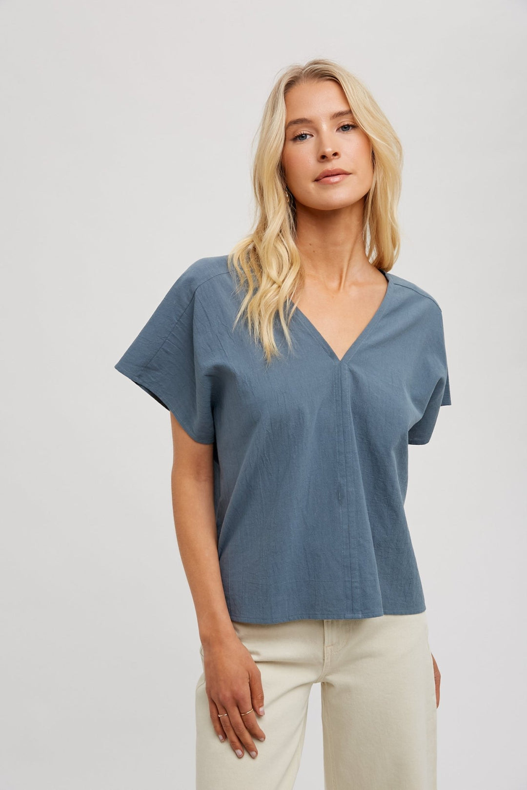 woman wearing a beige FUN2FUN V-neck top with dolman sleeves, showcasing the front view.