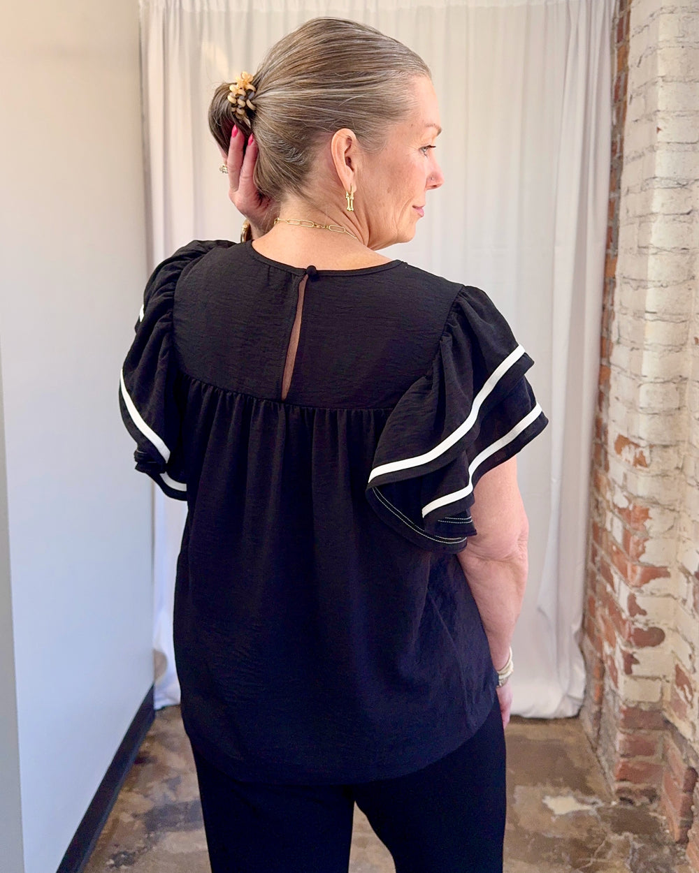 Carole Christian Game Day Ruffle Sleeve Textured Top in Black — keyhole button back detail close-up with white contrast ruffle sleeves, model wearing Small, Modish Maven Boutique