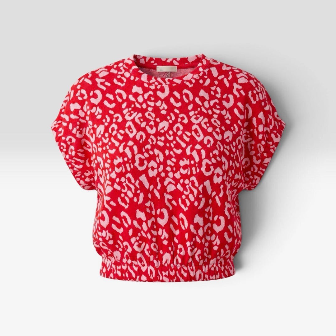 A red short-sleeve crop top with a white leopard print pattern, displayed on a neutral light gray background.