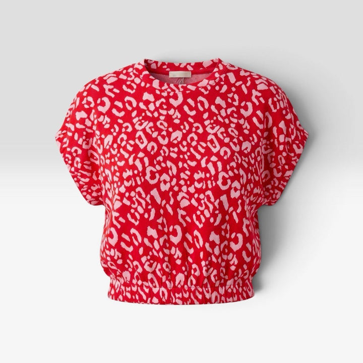 A red short-sleeve crop top with a white leopard print pattern, displayed on a neutral light gray background.