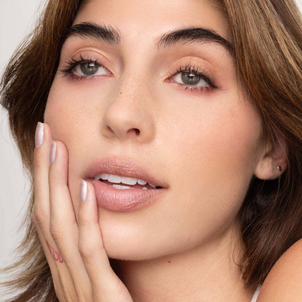 A close-up of Charlie Lip Tint applied to lips, showing a sheer nude color with cool undertones and a moisturizing finish.