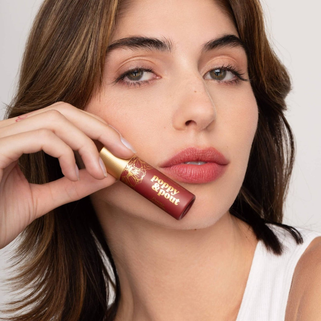A close-up of Penny Lip Tint applied to lips, showing a sheer, buildable red wash of color with a moisturizing, healthy glow.