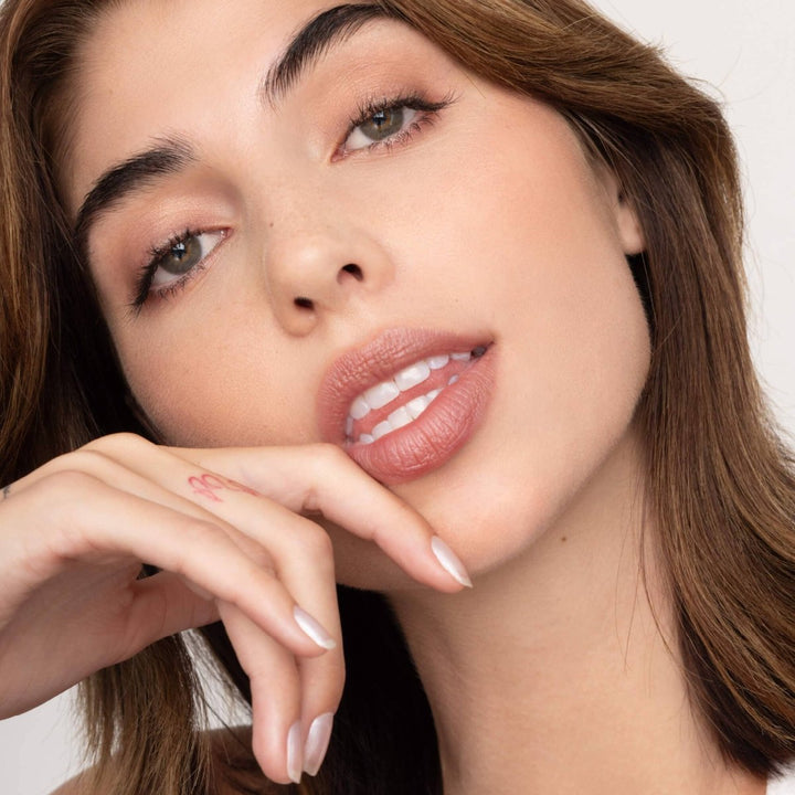 A close-up of Roxie Lip Tint applied to lips, showing a sheer, buildable brick red color with a moisturizing, healthy finish.
