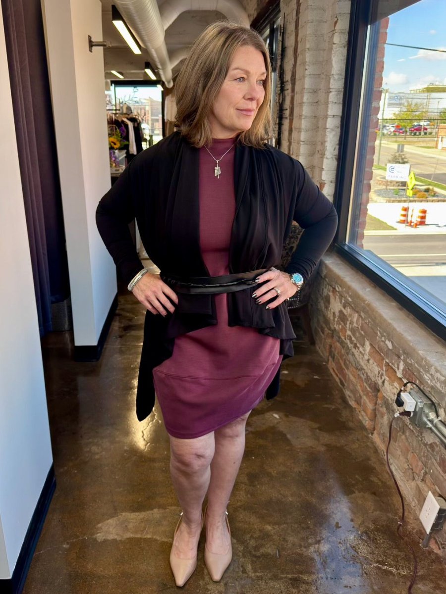 A sophisticated ensemble featuring the plum Juno Dress and a black cardigan cinched at the waist with a belt for a refined, effortless silhouette.
