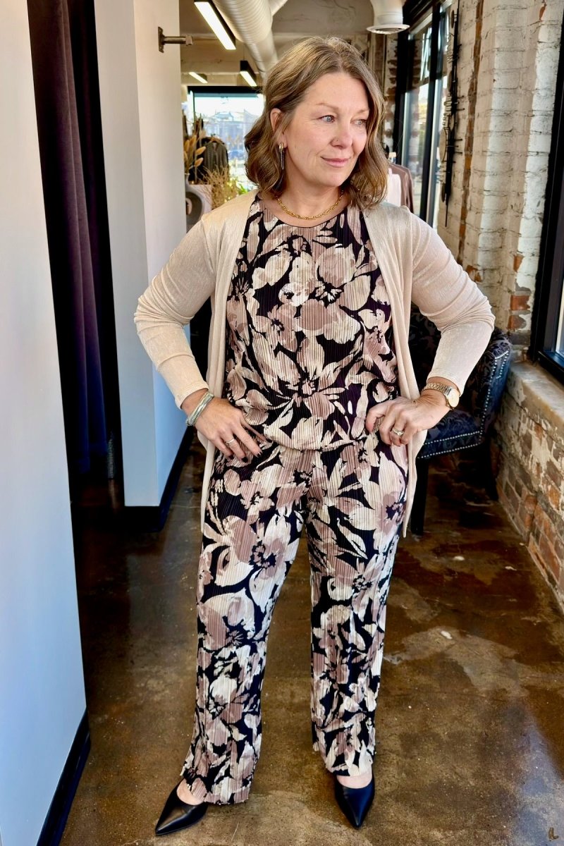 A chic outfit featuring a sleeveless floral jumpsuit layered under a lightweight cream-colored cardigan, showcasing an elegant and airy style perfect for transitioning seasons.