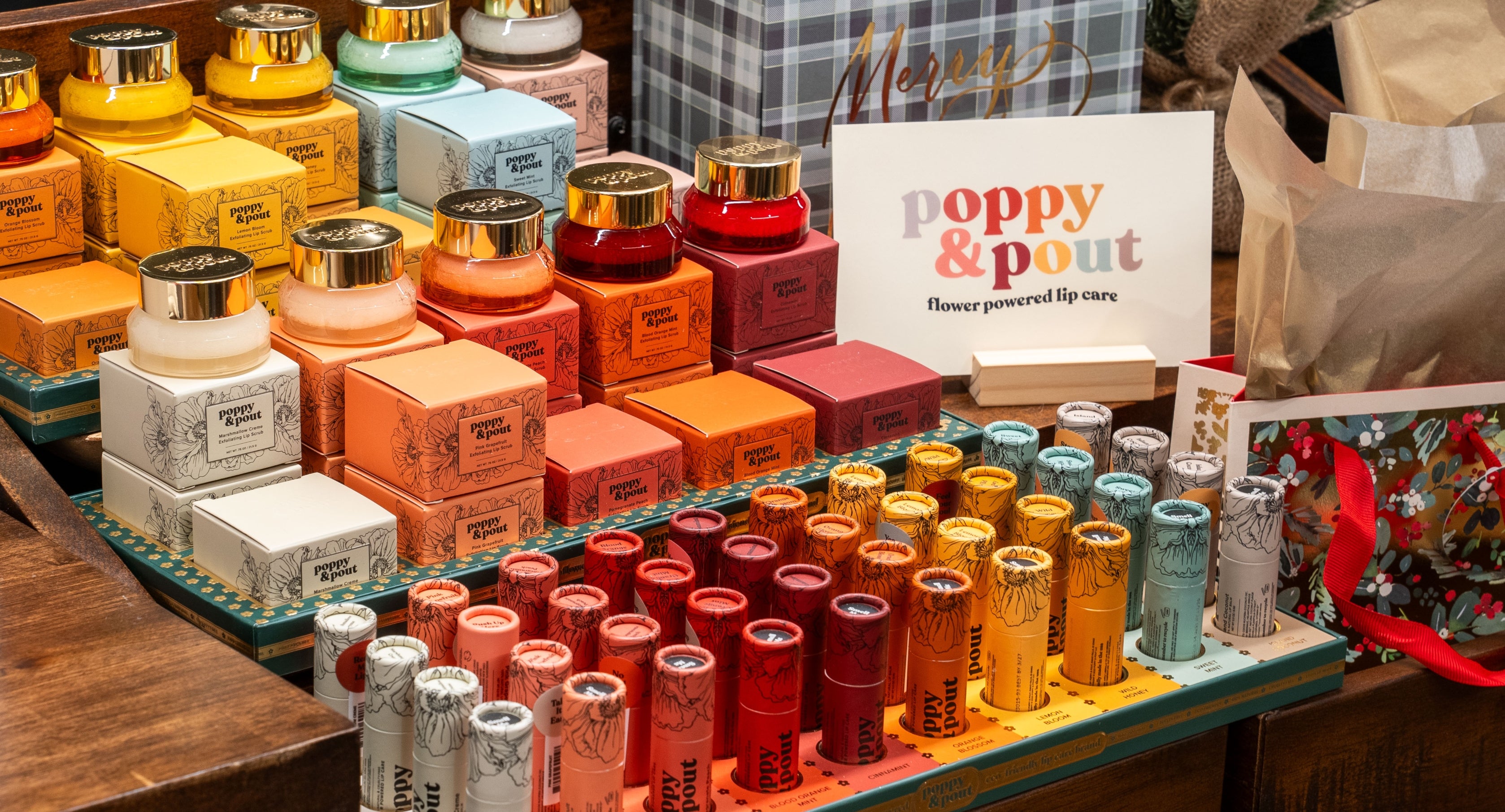 Display of lip balm containers with a 'Poppy & Pout' sign in the background.