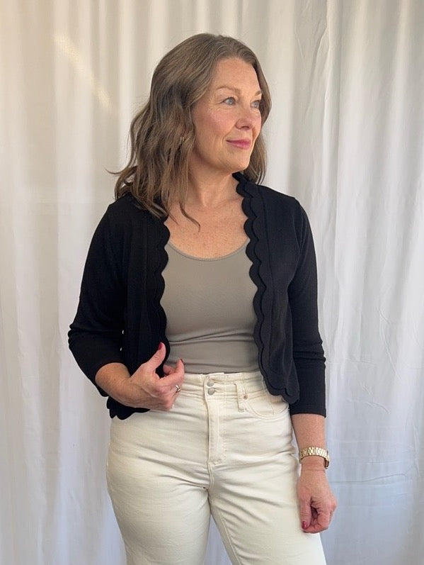 Zac &amp; Rachel Scallop Knit Shrug Cardigan in Black styled with taupe tank and cream wide-leg jeans, close front view on model
