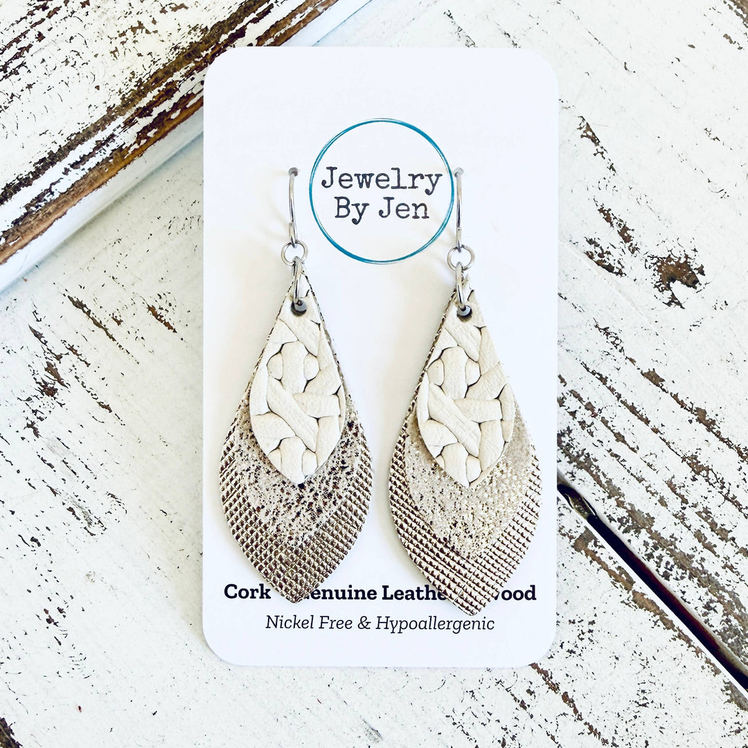 Pair of cork and leather earrings on a 'Jewelry By Jen' card with a wooden background.