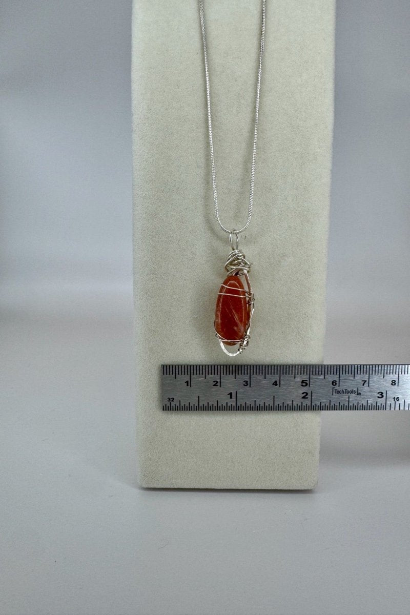 Wire-Wrapped Sunstone Pendant Necklace in Orange &amp; Silver — close-up of stone and wire wrapping beside a ruler