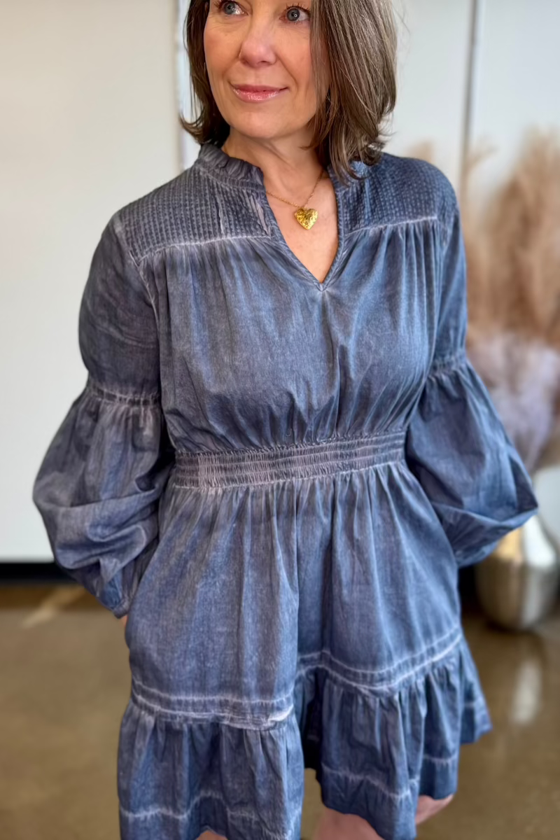 Close up of woman with hands in the pockets of a blue flowy dress.