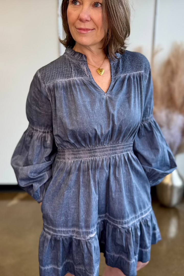 Close up of woman with hands in the pockets of a blue flowy dress.
