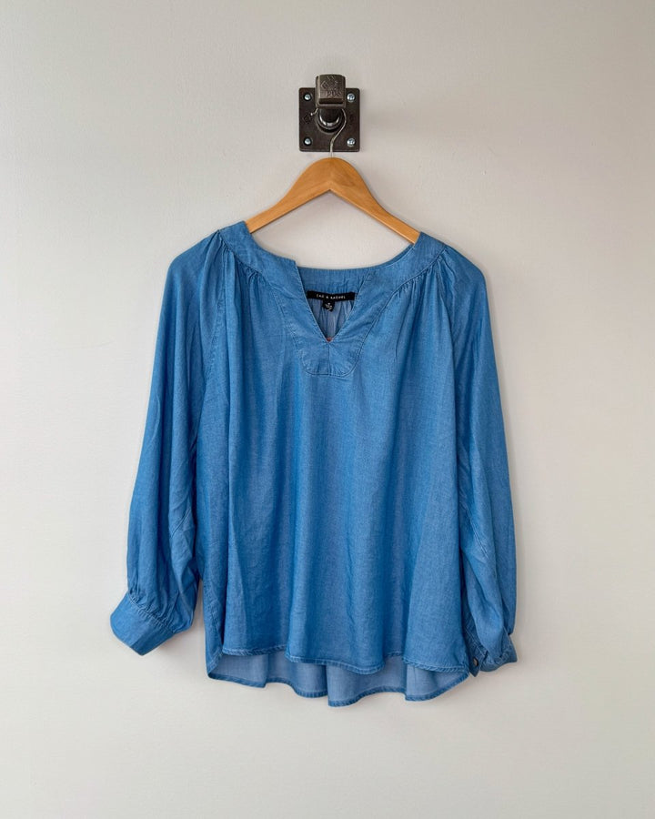 Blue blouse on a wooden hanger against a white wall