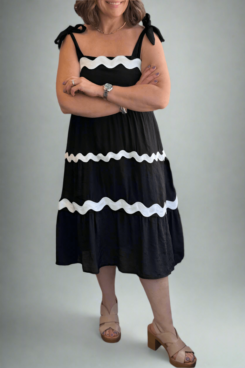 A flattering, tiered "Modern Midwest" midi dress featuring black tissue faille fabric and white ric rac accents.
