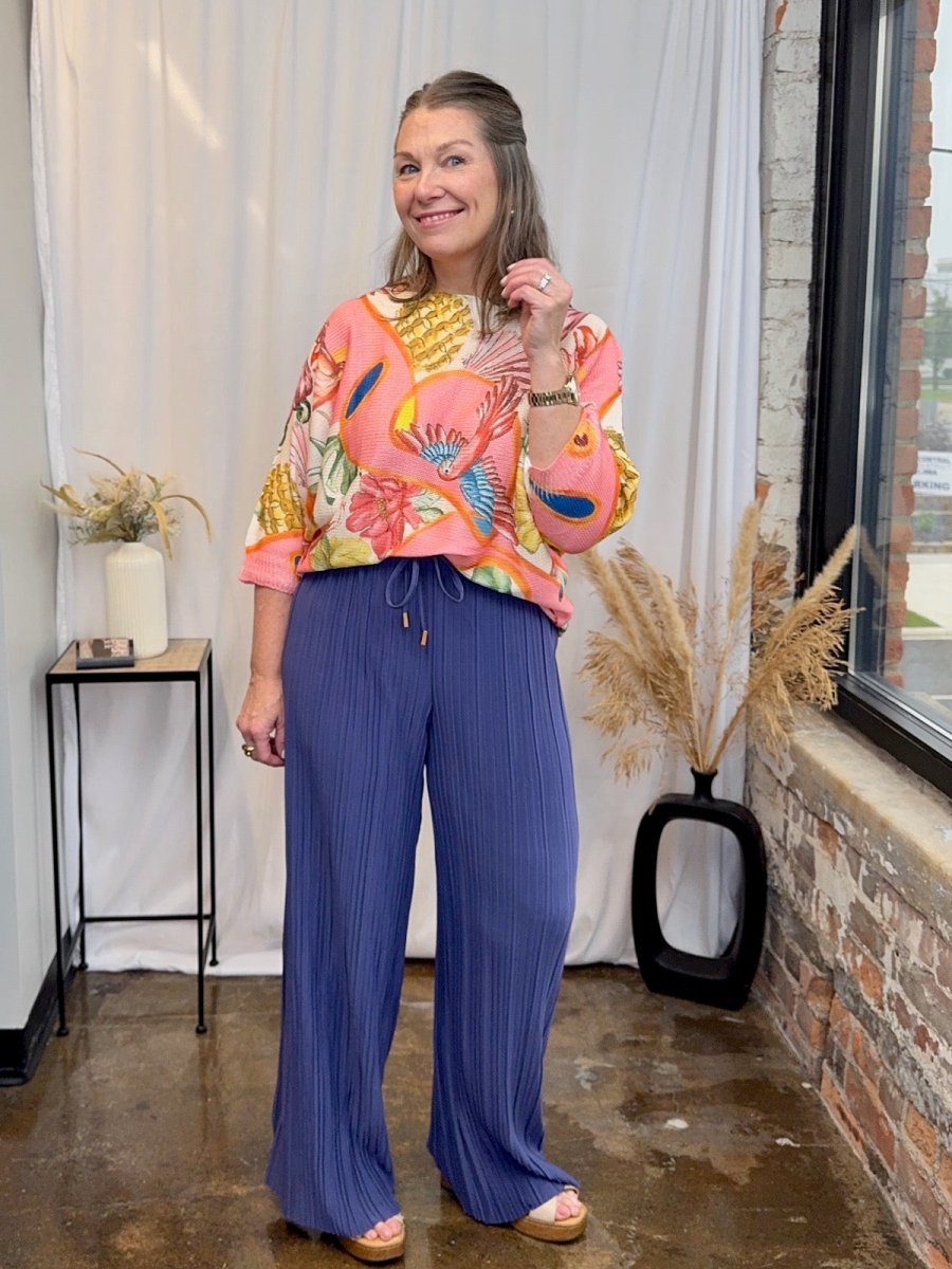 Styled look featuring the Made in Italy printed batwing top paired with blue pleated wide-leg trousers.