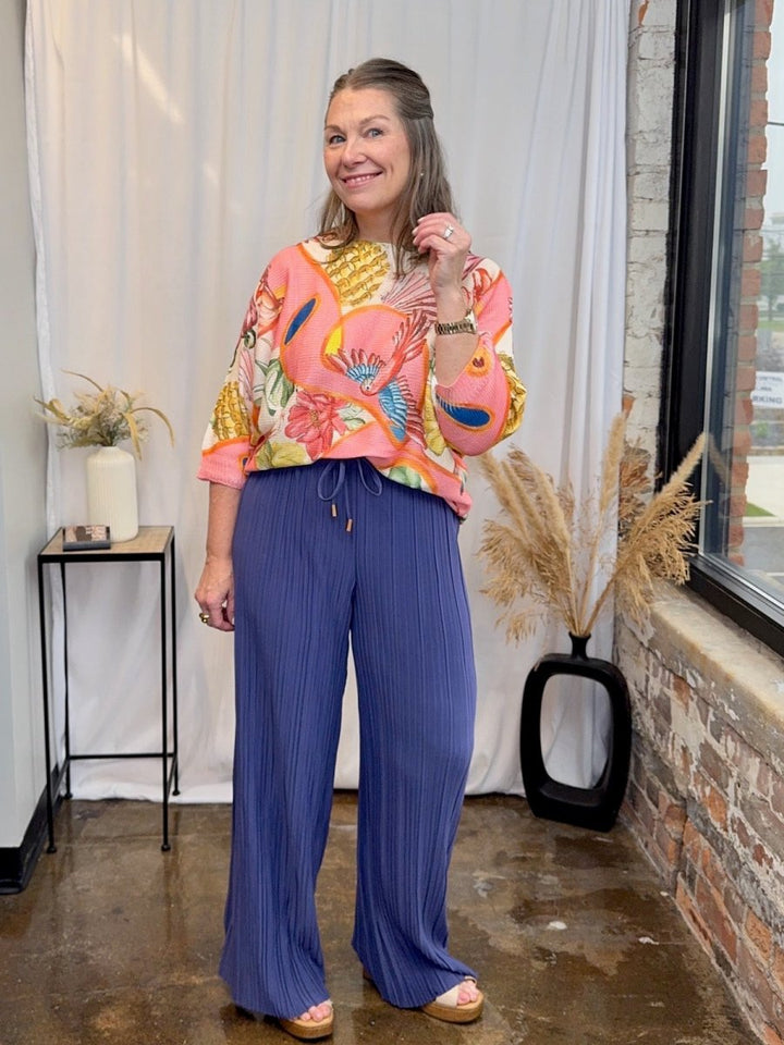 Styled look featuring the Made in Italy printed batwing top paired with blue pleated wide-leg trousers.