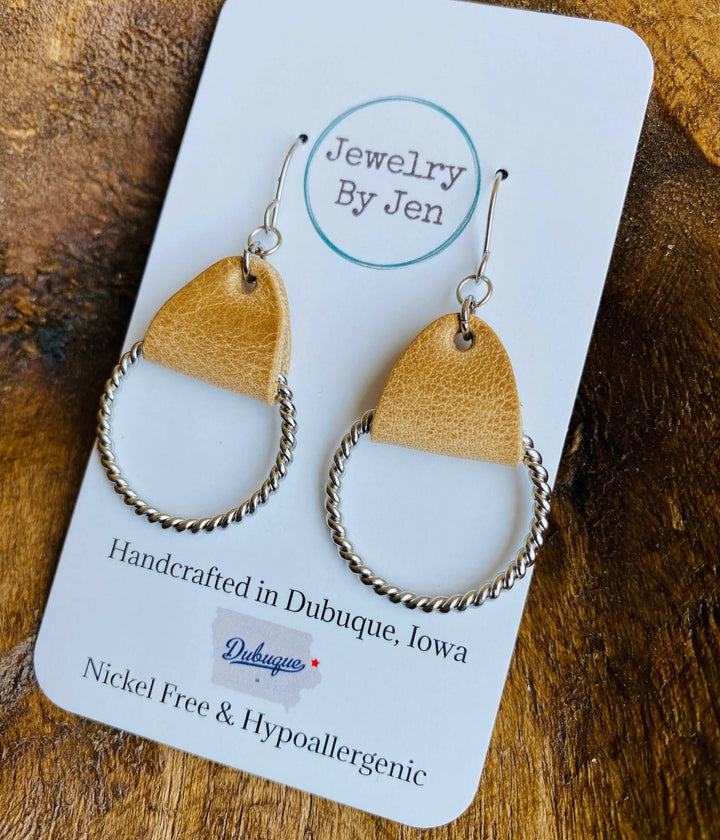 Silver and leather earrings on a product card.