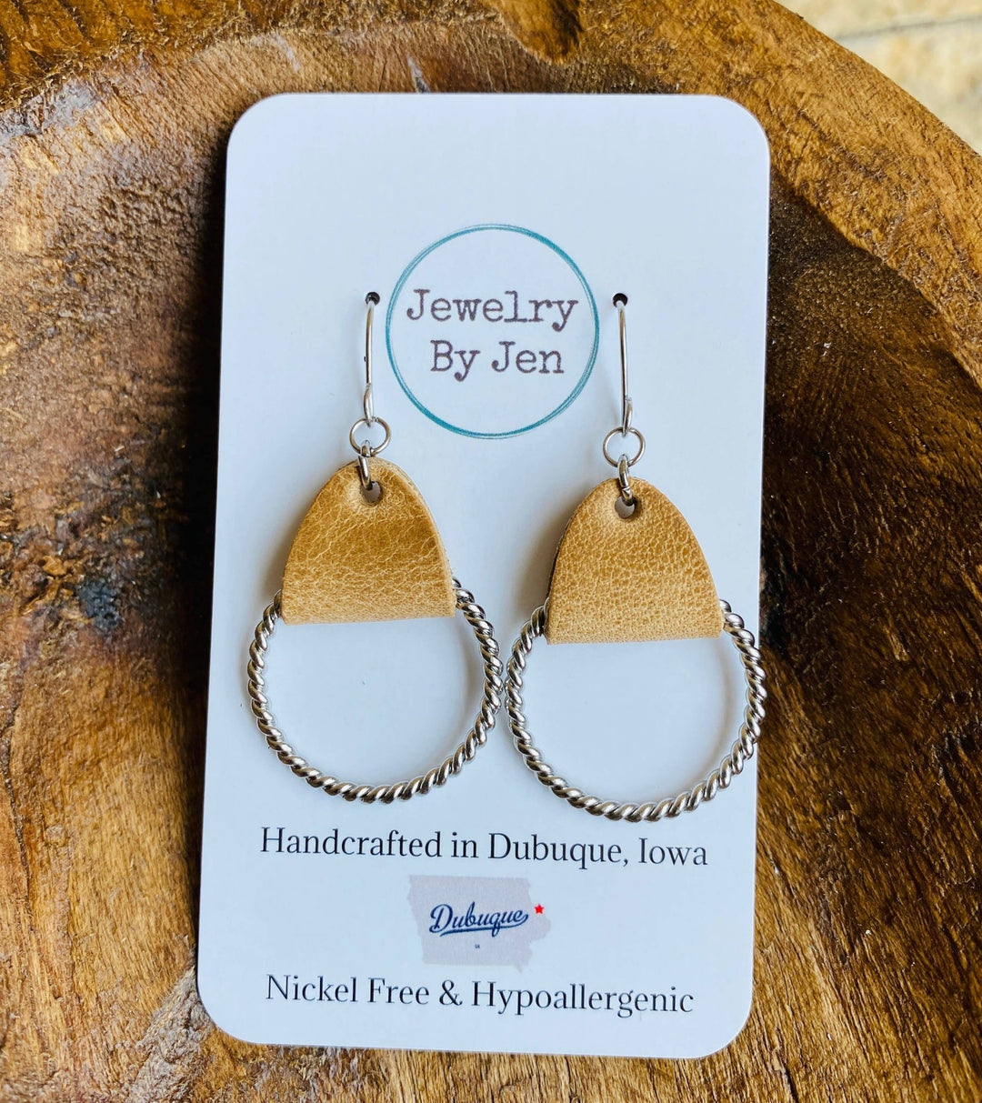 Twisted hoop earrings with weathered tan leather on a stainless steel hoop, displayed on a card with &