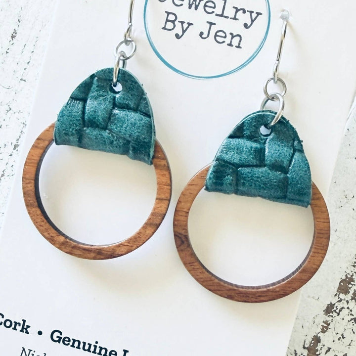 Pair of earrings with green cork and wood design on a white distressed surface with &