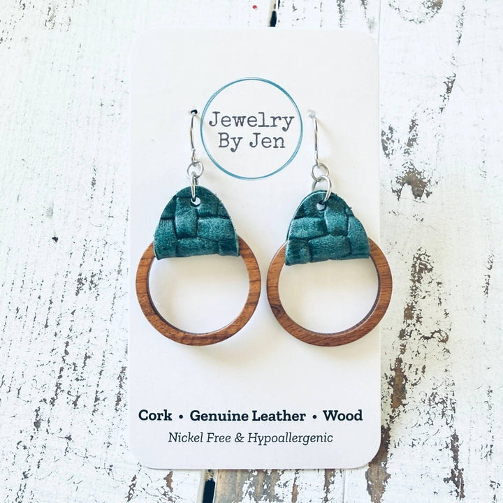 Pair of earrings with green leather and wooden design on a white card with &