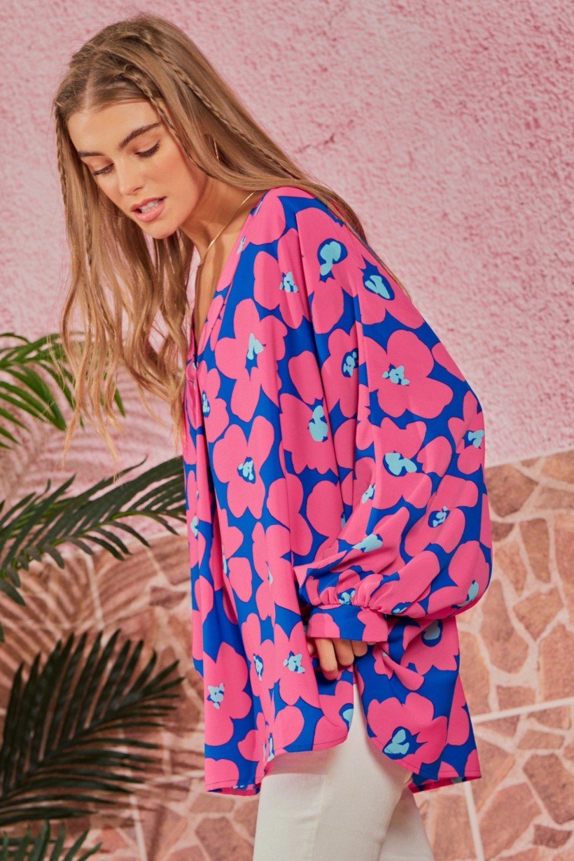 A side view of a model wearing a Floral V-Neck Dolman Top featuring an oversized pink and blue floral print with draped 3/4 sleeves.