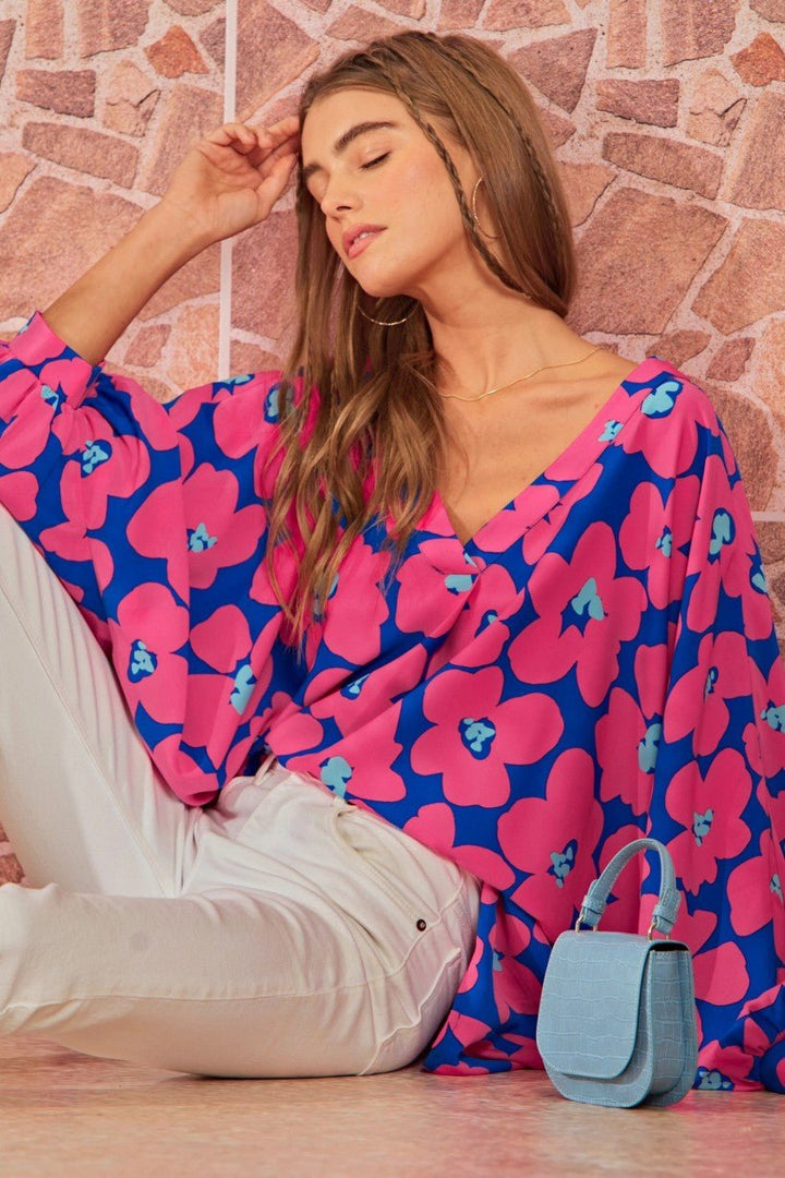 A close-up of a 3/4 length dolman sleeve and V-neckline on a non-sheer polyester top with a trendy oversized floral design.